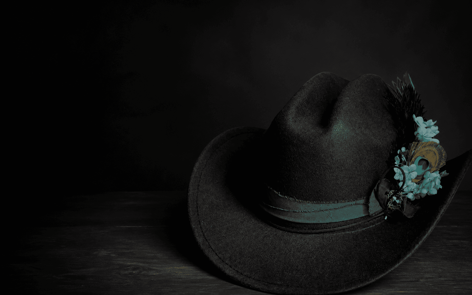 A handcrafted black Casa Pedrín hat with peacock feathers and turquoise flowers